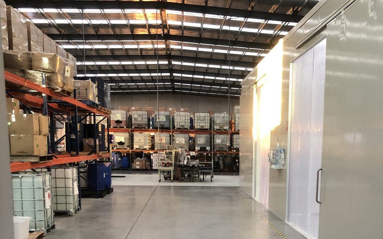 Manufacturing floor with pallet racking, raw material containers, a production bench and clean room panels
